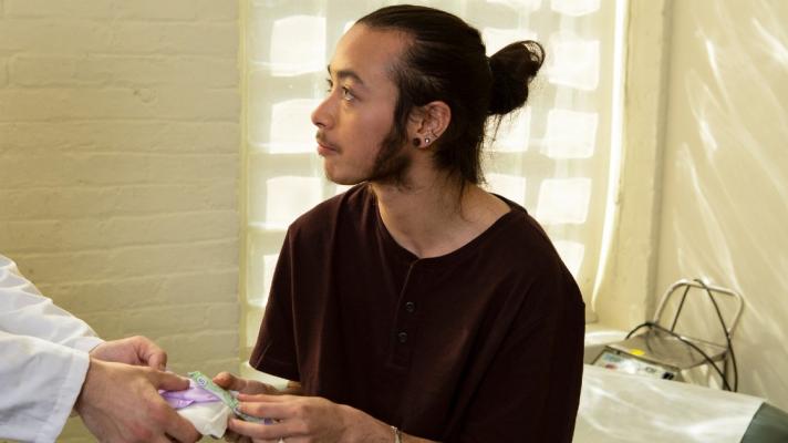 A genderqueer person receiving menstrual products from a doctor