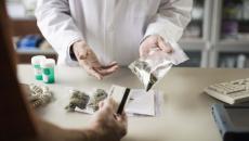 Person in lab coat showing person bags of cannabis