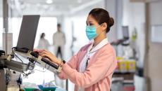 A clinician works in an EHR on a hospital floor.