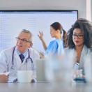 Healthcare workers meeting with large screen in background