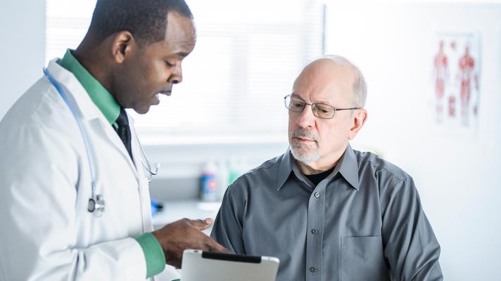 A doctor shows a patient some information on a tablet.