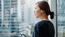 A person holding a smartphone looking out the window