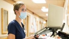 A nurse checking medication records on a laptop