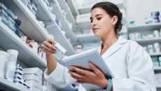 Pharmacist with a tablet looking at a medication box