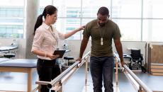 Physical therapist helping patient walk