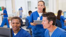 Nurses talking while looking at computer screen