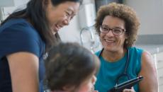 A female doctor laughs with a mother and daughter