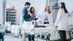 group of healthcare workers talking over hospital bed