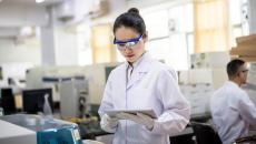 A female healthcare researcher in a lab looks at a tablet.