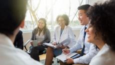 Laughing hospital administrators sitting down in a circle for a discussion