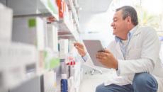 A pharmacist doing an inventory of medicines using a digital tablet