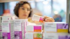 A pharmacist checking a box of medicine in a rack