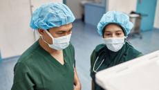 Two surgeons checking on an operation's progress through a digital monitor