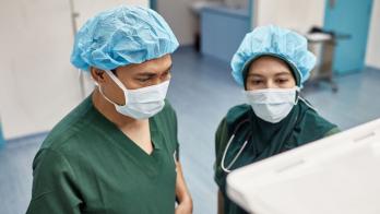 Two surgeons checking on an operation's progress through a digital monitor